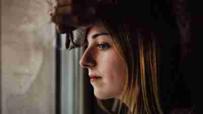 Woman with ADHD leans against window and wants to take an ADHD test for adult symptoms