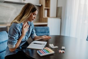 A young woman is taking medication from her pill organizer.