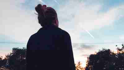 The silhouette of a ADHD woman looking at sunset in the distance.