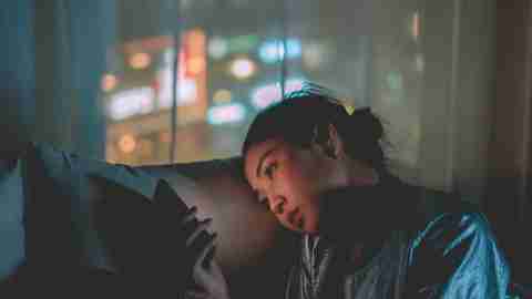 A tired woman resting on her couch while looking at her phone