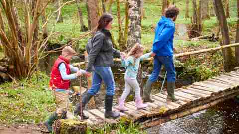 Parents with ADHD children walking across bridge on nature trail hike